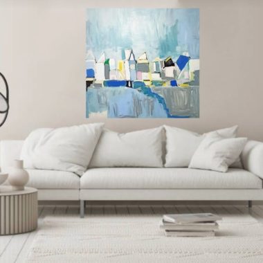 ציור מקורי: בסלון המינימליסטי יש ספה לבנה, שולחן קפה עגול וציור מופשט מודרני של בתים בצבעים כחול, צהוב ולבן על קיר בצבע בז', בשם