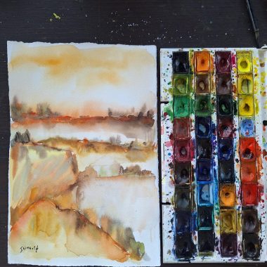 ציור מקורי: היצירה il_fullxfull.6557415931_2h6u.jpg מציגה צבעי מים מדבריים לצד פלטת צבעים עזה, עם מכחולים וכתמי צבע צבעוניים על שולחן עץ כהה, היוצרים נוף מופשט ומרהיב. מוסיף צבע וייחודיות לכל חלל.