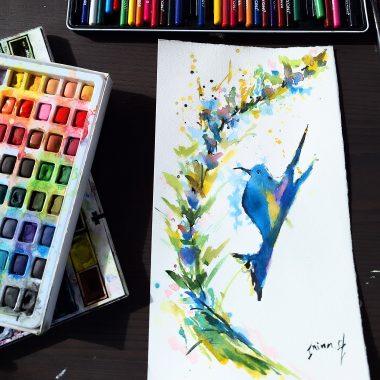 ציור מקורי: הקובץ il_fullxfull.5986983986_i0k4.jpg מציג ציור צבעוני מלא חיים של יונק דבש בגווני כחול, צהוב וירוק על נייר כותנה איכותי, המוצג על שולחן עם פלטת צבעי מים ועפרונות צבעוניים בסמוך. מוסיף צבע וייחודיות לכל חלל.