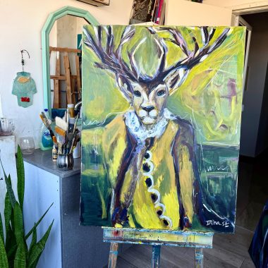 ציור מקורי: הקובץ il_fullxfull.6577556330_1jtj.jpg מציג ציור שמן צבעוני ומופשט של צבי בחליפה עם קרניים גדולות וצווארון מקומט על בד, הממוקם בסטודיו לאמנות עם ציוד אמנות, צמחים ומראה. מוסיף צבע וייחודיות לכל חלל.