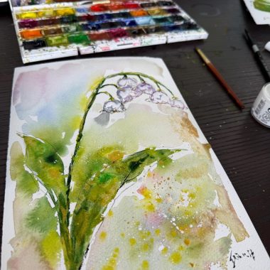 ציור מקורי: ציור בצבעי מים il_fullxfull.6613186886_hz32.jpg מציג שושן צחור על נייר לבן על גבי שולחן כהה, עם מכחולים, מיכל צבע וערכת צבעי מים בסמוך. גוונים רכים של ירוק וצהוב מפיחים חיים ביצירה. מוסיף צבע וייחודיות לכל חלל.