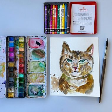 ציור מקורי: הקובץ il_fullxfull.6848435563_3ewq.jpg מציג ציור מקורי של חתול בצבעי מים על נייר כותנה, המונח לצד פלטת צבעים מעורבבים, קופסת פסטלים שמנים צבעוניים אדומה ומכחול על רקע לבן. מוסיף צבע וייחודיות לכל חלל.