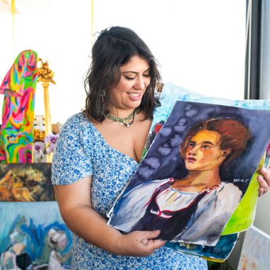 ציור מקורי: אישה בשמלה כחולה עם הדפס פרחוני מחייכת תוך שהיא מחזיקה ומתפעלת מ